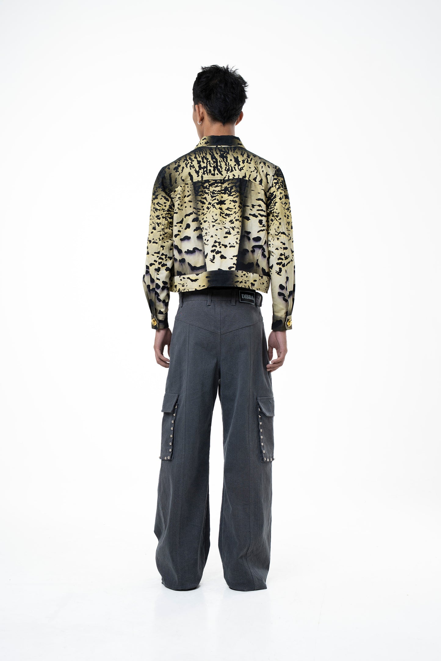 Person wearing a patterned jacket and gray pants on a white background